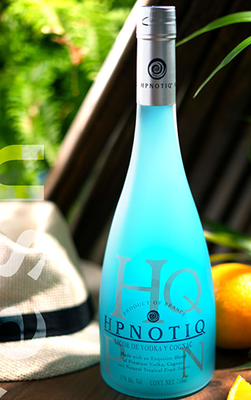 Botella de Hpnotiq en un entorno tropical